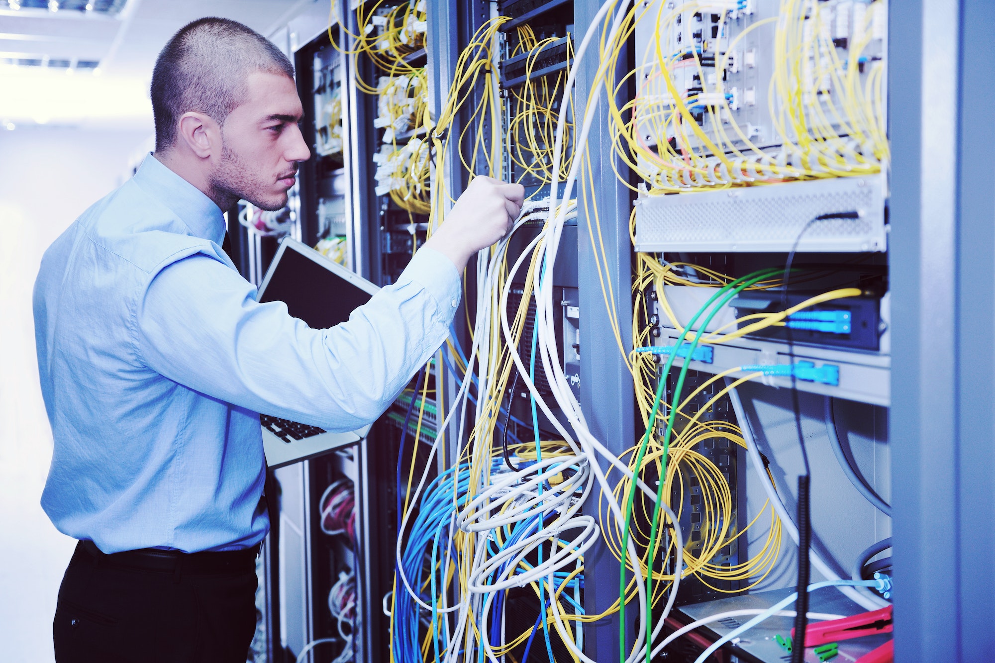 businessman with laptop in network server room